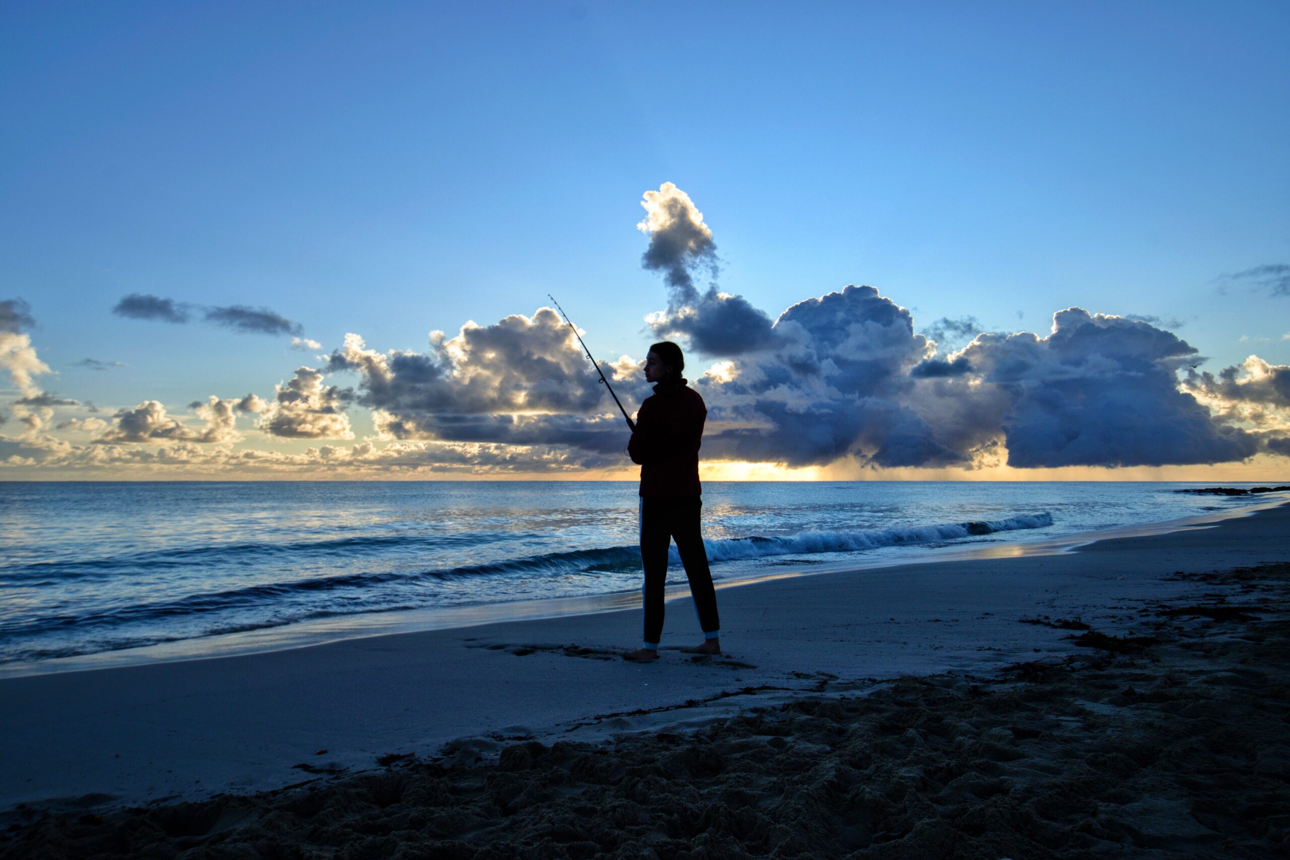 Angler surf fishing on a beach at sunrise along the North Carolina coast