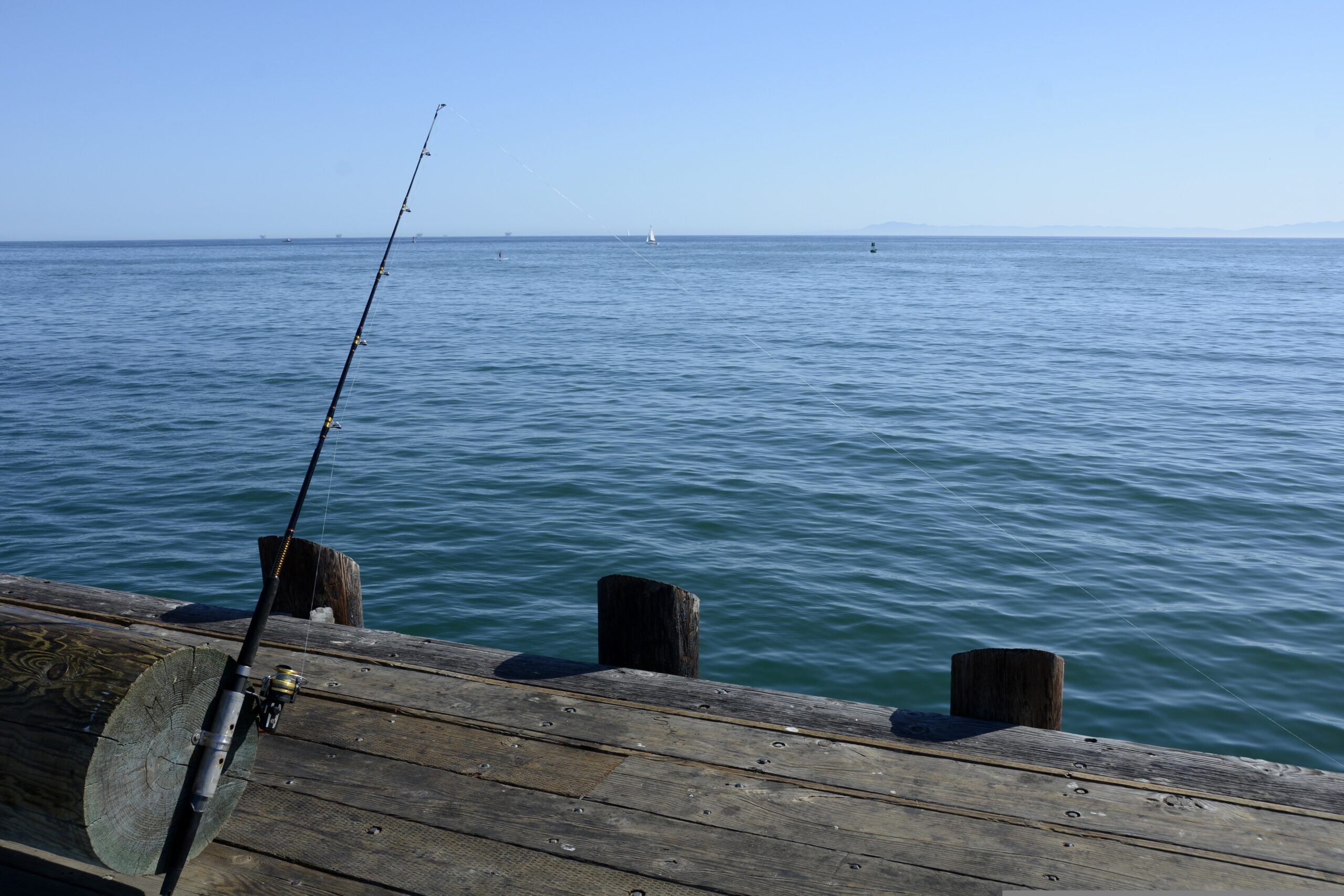 Fishing rod on a wooden pier overlooking the ocean